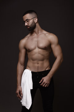 Topless man in dark pants against gray background
