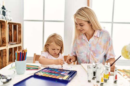 Mother and daughter smiling confident drawing on notebook at art studio