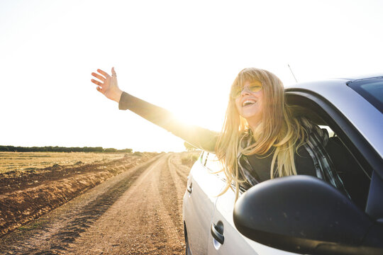 Woman enjoying fresh air out of car window on highway