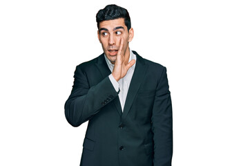 Handsome hispanic man wearing business clothes hand on mouth telling secret rumor, whispering malicious talk conversation
