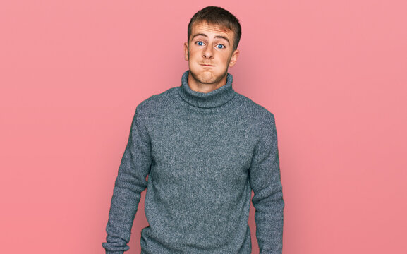 Young blond man wearing casual clothes puffing cheeks with funny face. mouth inflated with air, crazy expression.