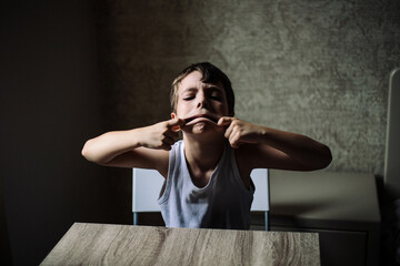  The boy grimaces and is naughty for the camera. Children's expression. Pampering. High quality photo