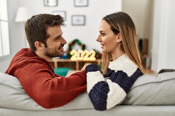Young hispanic couple smiling happy sitting on the sofa at home.