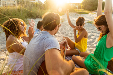 Outdoor fun on beach friends enjoying guitar music - Powered by Adobe