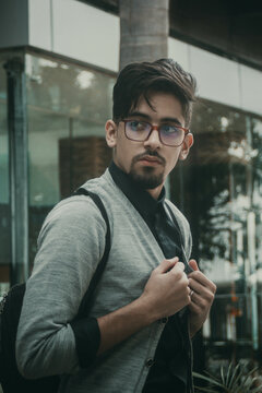 Young man in gray jacket with backpack sitting on a bench near store front
