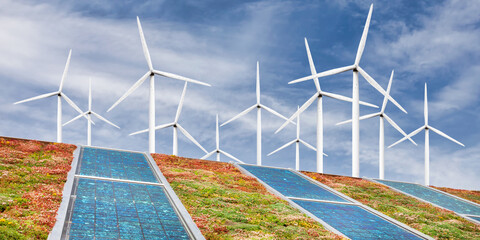 Green sedum roof with solar panels in front of wind turbines