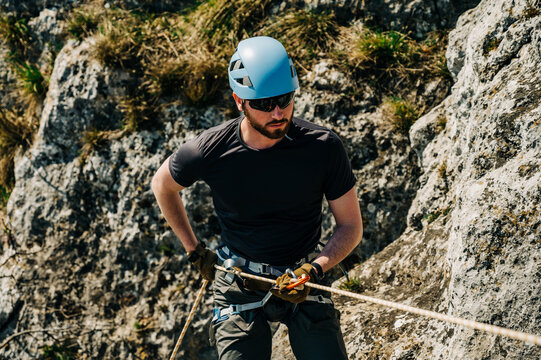 Young man with blue helmet rock climbing a cliff