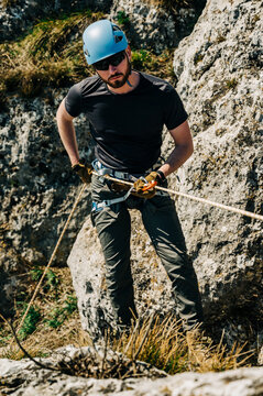 Young man with blue helmet rock climbing a cliff