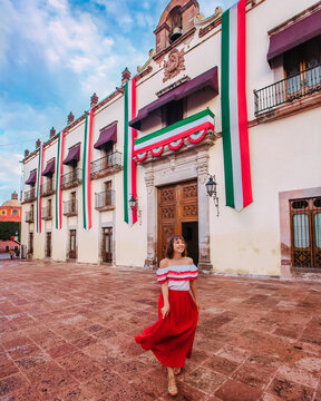 Young Mexican woman in red dress standing against Alameda Hidalgo in Mexico