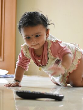Young South Asian baby crawling toward the TV remote control