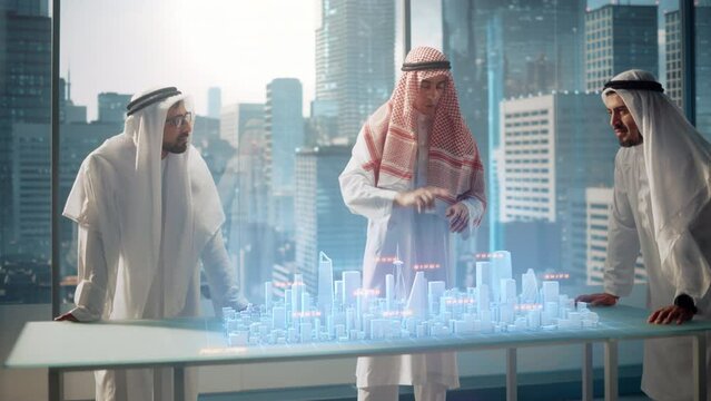 Group of Muslim Real Estate Business Developers in Traditional Clothes Discuss Investing Opportunities Based on Holographic Augmented Reality 3D City Model in Their Modern Office in a Skyscraper. 