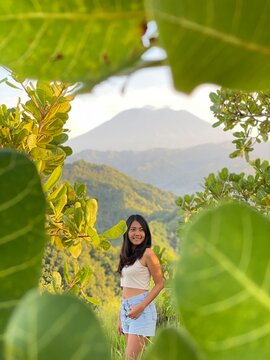 Young woman in denim shorts standing near trees in Bukit Tengah, Kelungkung, Bali
