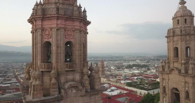 Drone flies over Morelia, Mexico at sunrise. Drone panning right close to the cathedral spires as the city wakes up. Part 1.