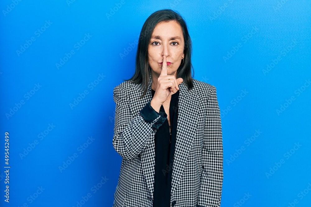 Sticker Middle age hispanic woman wearing business clothes asking to be quiet with finger on lips. silence and secret concept.