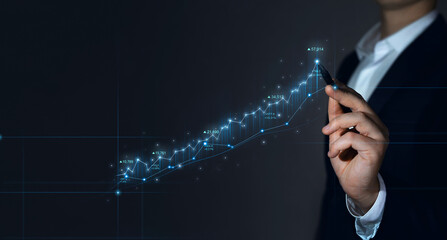 Businessman draws growing virtual hologram of statistics, graph and chart. Stock market and...