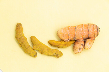 fresh turmeric dry root slices isolated on yellow background, top view