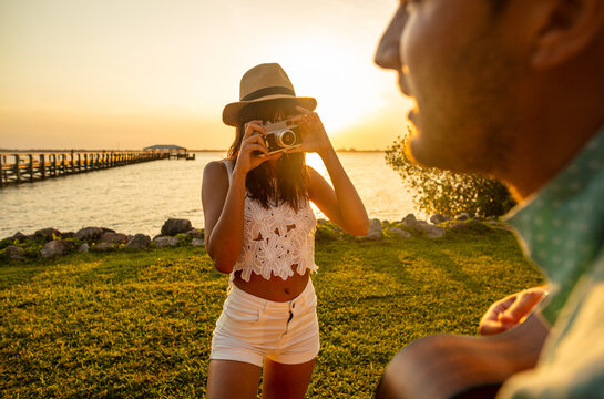 Ethnic female taking photograph of partner playing guitar