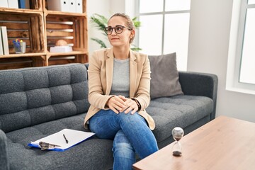 Obraz premium Young woman working at consultation office smiling looking to the side and staring away thinking.