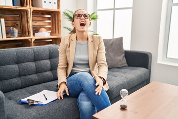 Obraz premium Young woman working at consultation office angry and mad screaming frustrated and furious, shouting with anger. rage and aggressive concept.