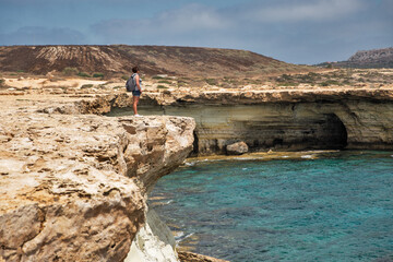 Woman standing over a cliff. Cape Greco peninsula park, Cyprus.