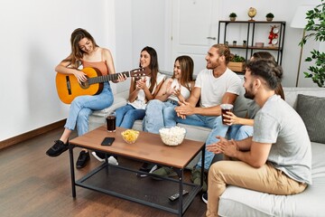 Group of young friends having party playing spanish guitar at home.