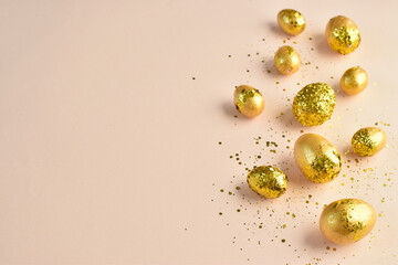 Easter eggs with gold sequins on a beige background.