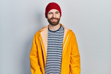 Caucasian man with beard wearing yellow raincoat winking looking at the camera with sexy...