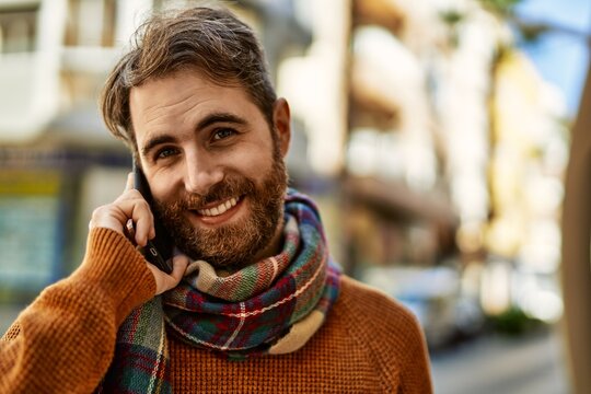 Caucasian man with beard having a conversation speaking on the phone outdoors on a sunny day