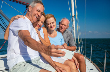 Retired friends relaxing on luxury yacht taking photographs