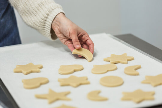 Confectioner cutting dough with different shapes while making cookies in the kitchen of the bakery.