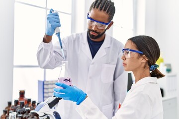 Man and woman scientist partners working using test tube and pipette at laboratory