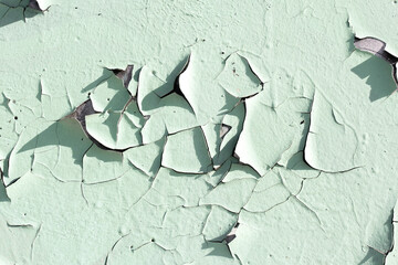 Mint colored wall with peeling paint, cracks on the wall