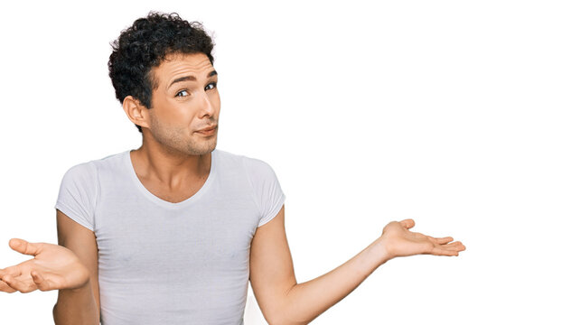 Young handsome man wearing casual white t shirt clueless and confused expression with arms and hands raised. doubt concept.