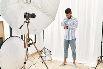 Arab young man posing as model at photography studio looking at the watch time worried, afraid of...