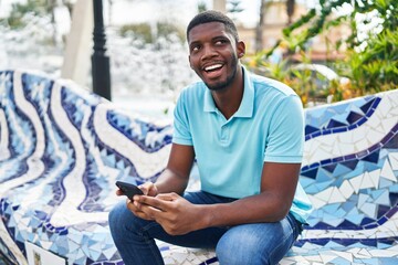 Young african american man smiling confident using smartphone at park