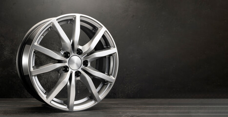 new grey alloy wheels on a dark textured black background. car wheel , copy space panorama empty...