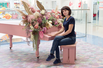 Young beautiful woman sitting piano decorated with flowers.