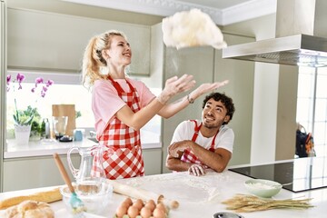 Young couple smiling happy cooking dough at kitchen.