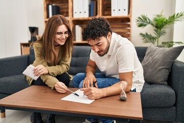 Fototapeta premium Man and woman having psychology session writing on paperwork at psychology center