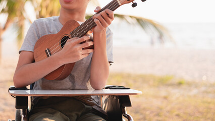 Fototapeta na wymiar Hand of young man with disability holding ukulele and singing, playing with music therapy on the outdoor nature background,Vacation hobby activity with family activity and mental health concept.