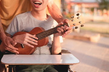 Hand of young man with disability holding ukulele and singing, playing with music therapy on the...