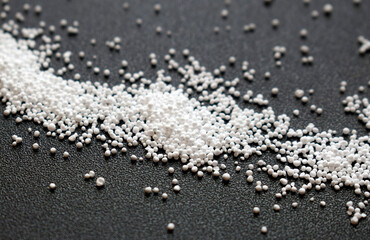 Small round granules on a black background. Laundry bleaching powder in granules.