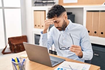 Naklejka premium Young hispanic man business worker stressed using laptop working at office