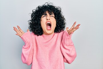 Young middle east woman wearing casual clothes crazy and mad shouting and yelling with aggressive expression and arms raised. frustration concept.
