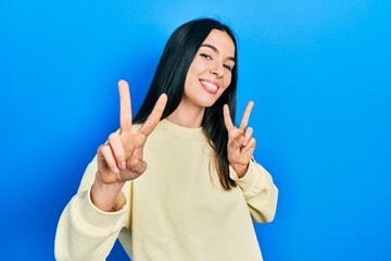 Young brunette woman wearing casual sweatshirt smiling looking to the camera showing fingers doing...