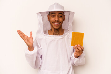 Young African American beekeeper isolated on white background receiving a pleasant surprise,...