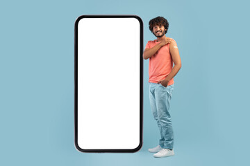 Healthy indian guy with medical band on shoulder and smartphone
