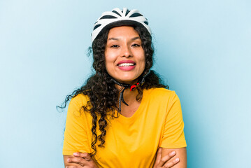 Young hispanic woman wearing a helmet bike isolated on blue background laughing and having fun.