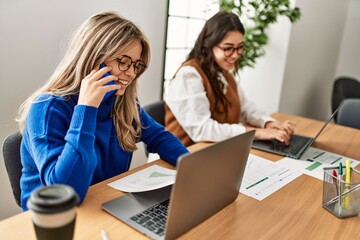 Two business workers woman talking on the smartphone and using laptop at the office.