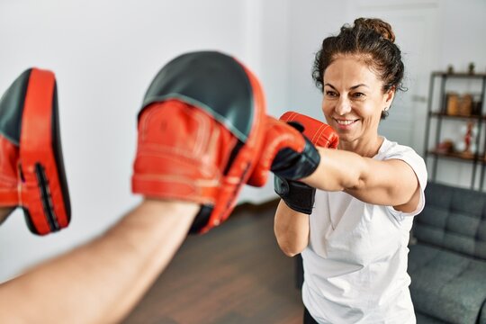 Middle age hispanic couple smiling happy training boxing at home.